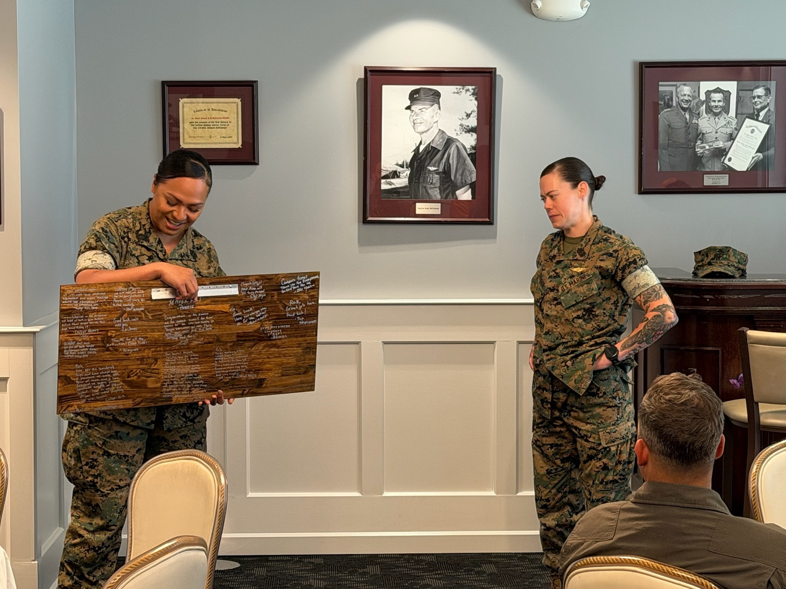 Two Marines share a retirement plaque during a unit gathering